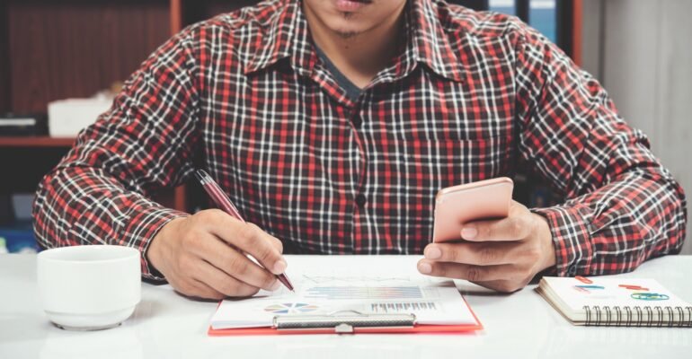 close-up-young-man-working-smart-phone-laptop-min